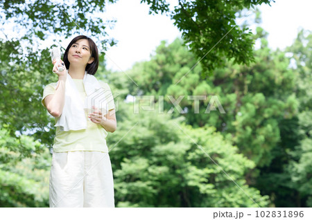 木陰で扇風機と水を持つ女性 102831896