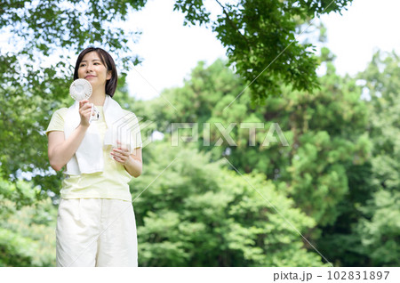 木陰で扇風機と水を持つ女性 102831897