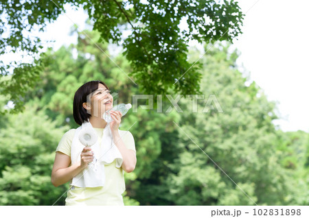 木陰で扇風機と水を持つ女性 102831898