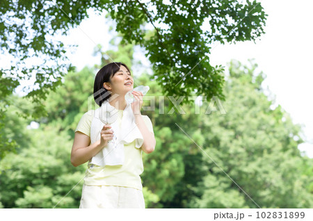 木陰で扇風機と水を持つ女性 102831899