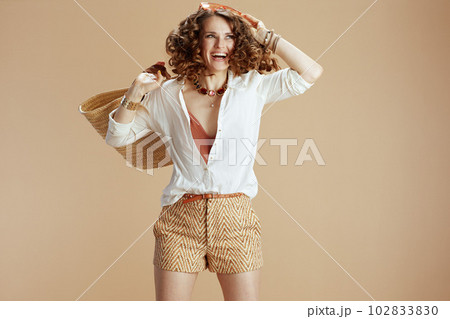 smiling woman in blouse and shorts jumping on beige smiling woman in blouse and shorts jumping on beige 102833830