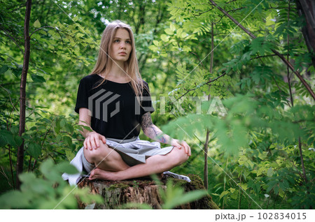 Practice of meditation and interaction with nature. Girl in green forest 102834015