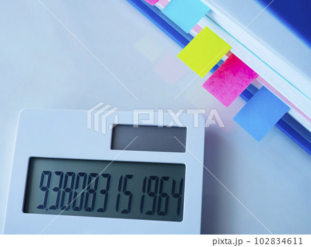 テーブルに置かれた青いファイルと電卓 102834611