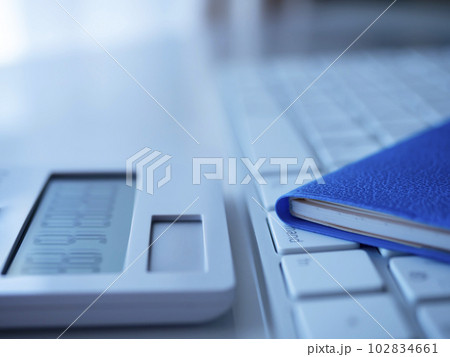 青い手帳とキーボード、電卓のビジネスイメージ  102834661