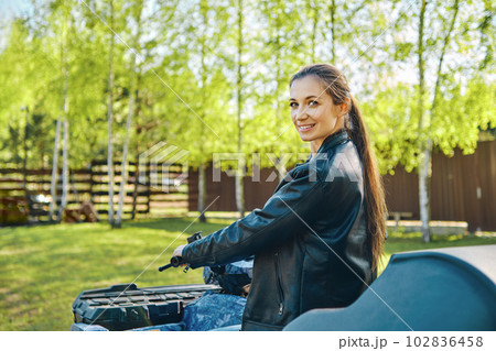 Cheerful woman on quad bike looking back Cheerful woman on quad bike looking back 102836458