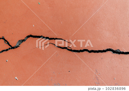 Crack in red-painted asphalt on a sports field 102836896