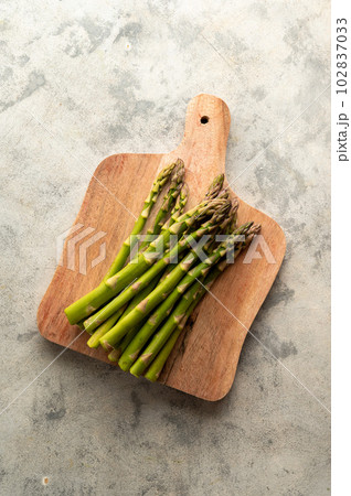 Fresh asparagus on wooden chopping board, top view 102837033