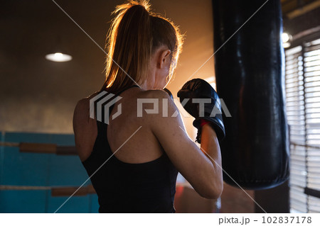 Women self defense girl power. Strong woman fighter training punches on boxing ring. Healthy strong girl punching boxing bag. Training day in boxing gym. Strength fit body workout training Women self defense girl power. Strong woman fighter training punches on boxing ring. Healthy strong girl punching boxing bag. Training day in boxing gym. Strength fit body workout training 102837178