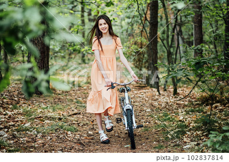 Walk in the woods for wellness, Health benefits of forests. Immerse Yourself in a Forest. A young girl rolls a bicycle along a forest path in tree wood 102837814