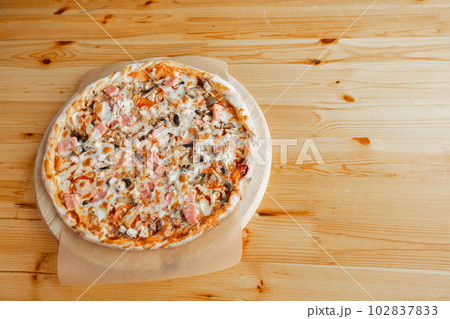 Closeup hand of chef baker in uniform blue apron cutting pizza at kitchen Closeup hand of chef baker in uniform blue apron cutting pizza at kitchen 102837833