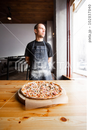 chef baker in uniform blue apron cutting pizza at kitchen chef baker in uniform blue apron cutting pizza at kitchen 102837840