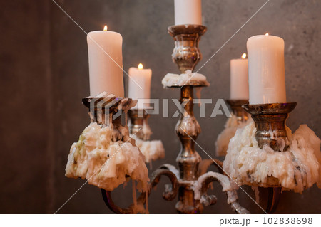 Light candle in the brass candlestick closeup on a dark background. Light candle in the brass candlestick closeup on a dark background. 102838698