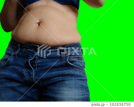 Saggy belly. Folds of leather and fat on the sides hanging over the waist of the jeans. Overeating or pregnancy. Obesity and Diabetes. Green chroma key background. Cellulite flabby muscles Saggy belly. Folds of leather and fat on the sides hanging over the waist of the jeans. Overeating or pregnancy. Obesity and Diabetes. Green chroma key background. Cellulite flabby muscles 102838750