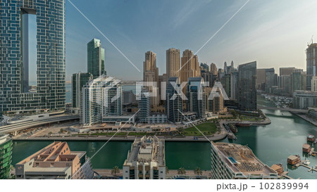 Panorama showing Dubai Marina with several boats and yachts parked in harbor and skyscrapers around canal aerial morning timelapse. Panorama showing Dubai Marina with several boats and yachts parked in harbor and skyscrapers around canal aerial morning timelapse. 102839994