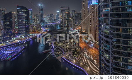 Aerial view to Dubai marina skyscrapers around canal with floating boats night timelapse Aerial view to Dubai marina skyscrapers around canal with floating boats night timelapse 102840050
