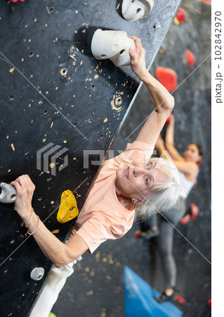 elderly active female pensioner reached top of bouldering wall elderly active female pensioner reached top of bouldering wall 102842970