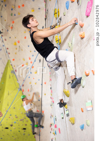 Determined young man doing his best at climbing artificial wall 102842976