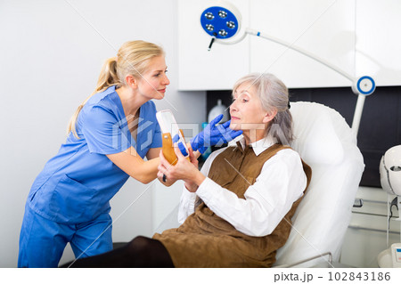 Cosmetologist explaining future facial procedure to elderly female patient Cosmetologist explaining future facial procedure to elderly female patient 102843186