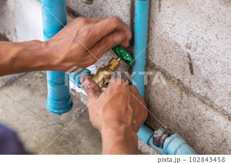A Mechanic Plumber is Repairing a Leaking Water Pipe Tap Near the Water Meter A Mechanic Plumber is Repairing a Leaking Water Pipe Tap Near the Water Meter 102843458