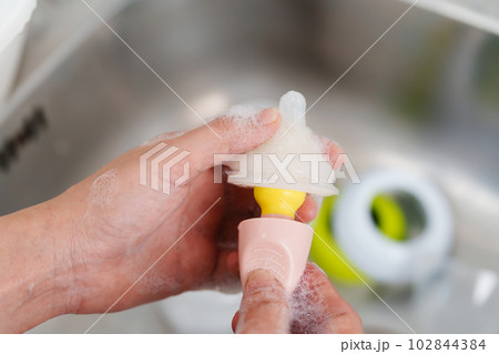mother hand washing the baby nipple of milk bottle 102844384