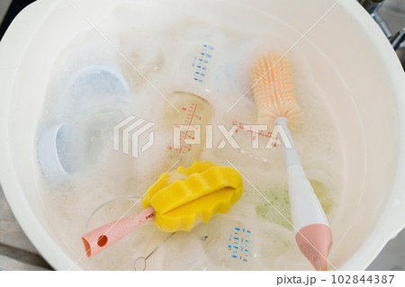 bottle of milk with brush are washing in basin 102844387