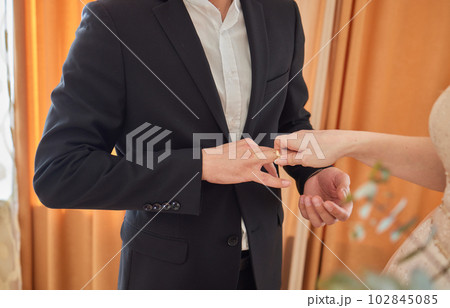 the bride in a dressing gown puts a wedding ring on her finger. the bride in a dressing gown puts a wedding ring on her finger. 102845085