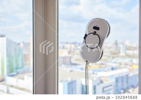 A window cleaner robot washes glass against the backdrop of multi-storey buildings. A window cleaner robot washes glass against the backdrop of multi-storey buildings. 102845688