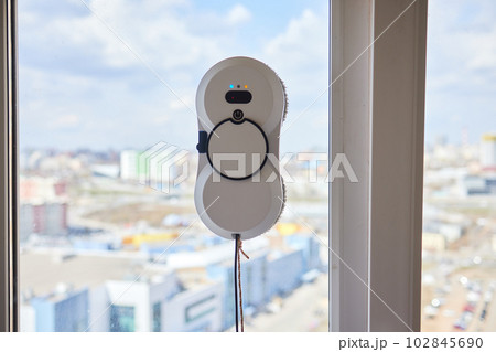 A window cleaner robot washes glass against the backdrop of multi-storey buildings. A window cleaner robot washes glass against the backdrop of multi-storey buildings. 102845690