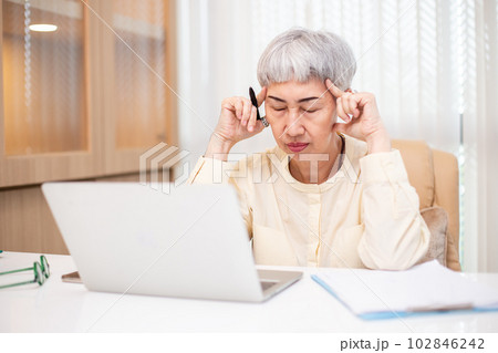 Asian senior business woman stress from hard work, Female manager headache sitting at table. 102846242