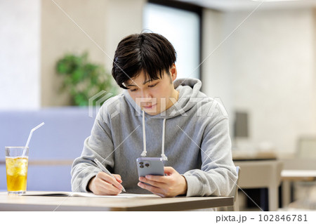 カフェでスマホを見ながら勉強をする学生 102846781