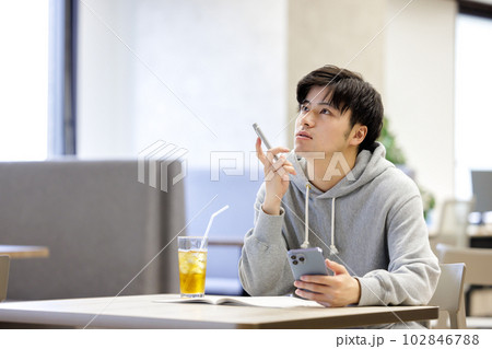 カフェでスマホを見ながら勉強をする学生 102846788