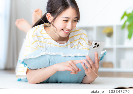 部屋でスマホを操作する若い女性 部屋でスマホを操作する若い女性 102847276