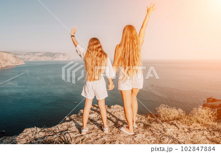 Sea family vacation together, happy mom and teenage daughter hugging and smiling together over sunset sea view. Beautiful woman with long hair relaxing with her child. Concept of happy friendly family Sea family vacation together, happy mom and teenage daughter hugging and smiling together over sunset sea view. Beautiful woman with long hair relaxing with her child. Concept of happy friendly family 102847884