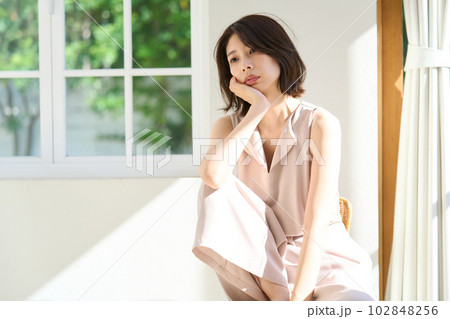窓際で日差しを浴びる若い女性 102848256
