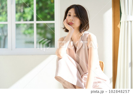窓際で日差しを浴びる若い女性 102848257