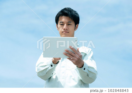 空を背景にタブレットを持つ作業服のビジネスマン 102848843