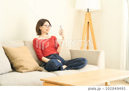 私服の若い女性 リビング スマホ 私服の若い女性 リビング スマホ 102849491