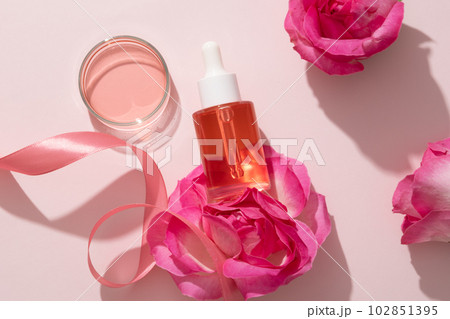 Natural skin care concept with pink liquid extracted from Rose (Rosa) contained inside a glass petri dish and a glass bottle with dropper. Branding mockup 102851395