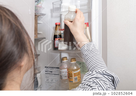 【冷蔵室からソースを出す主婦】 102852604