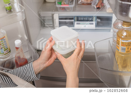 【冷蔵室からタッパを取り出す主婦】 102852608