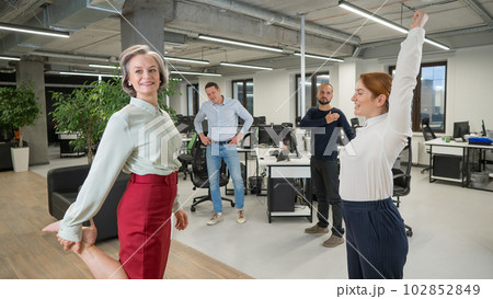 Four office workers warm up during a break. Employees do fitness exercises at the workplace. Four office workers warm up during a break. Employees do fitness exercises at the workplace. 102852849