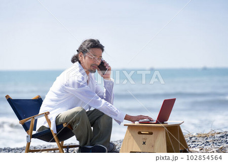 海辺でPC作業をする男性　テレワーク　ワーケーション　イメージ 102854564