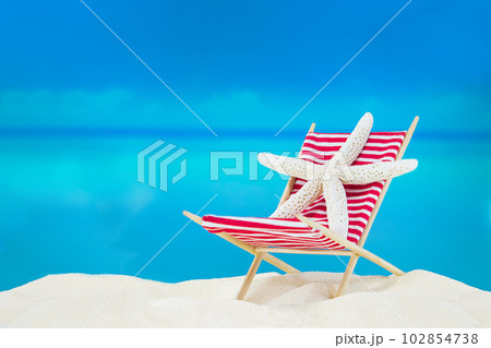 White starfish on striped red sunbed on sand of beach behind sea. Summer, travel vacation in hot countries. Copy space 102854738