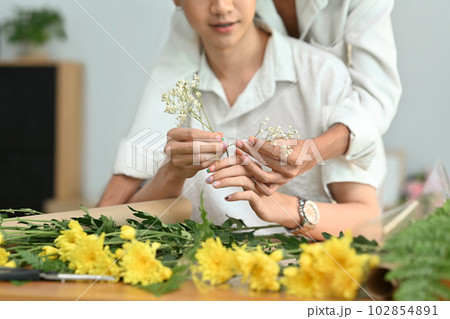 Affectionate romantic male gay couple spending time together, enjoying arranging flowers in cozy home. LGBT, homosexual and love 102854891