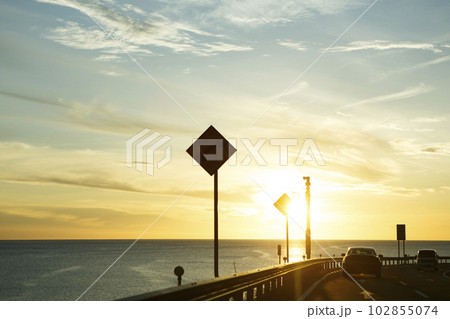 海沿いを走る道から見える夕焼け 102855074
