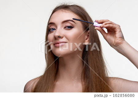 Beautiful young woman applying black mascara on long thick eyelashes 102856080