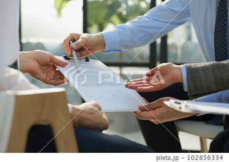 Businessman passing document to manager at the office Businessman passing document to manager at the office 102856334