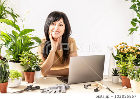 Smiling female using laptop computer at workshop transplantation houseplants 102856867