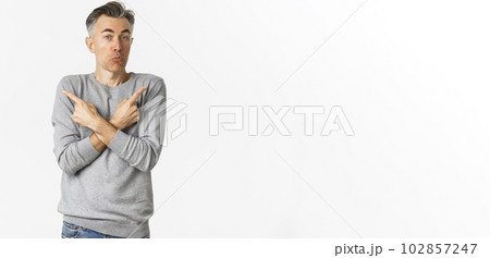 Image of handsome middle-aged man shrugging clueless, pointing fingers sideways at left and right variants, need help with choice, standing over white background 102857247