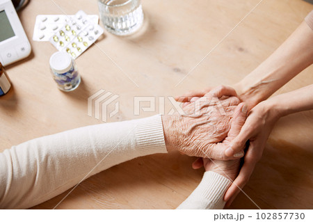 Close-up image of doctor's hand holding senior female patient hands, giving support and hope. Close-up image of doctor's hand holding senior female patient hands, giving support and hope. 102857730